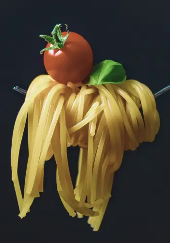 Fork with spaghetti, tomato, and basil symbolising Design Your Italy's tailored travel consultancy services.